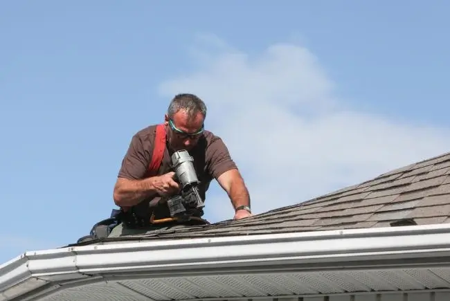 man applying sealant evenly to install new shingles